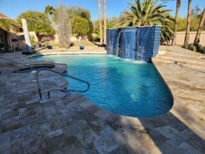 Backyard pool with waterfall and palm trees.