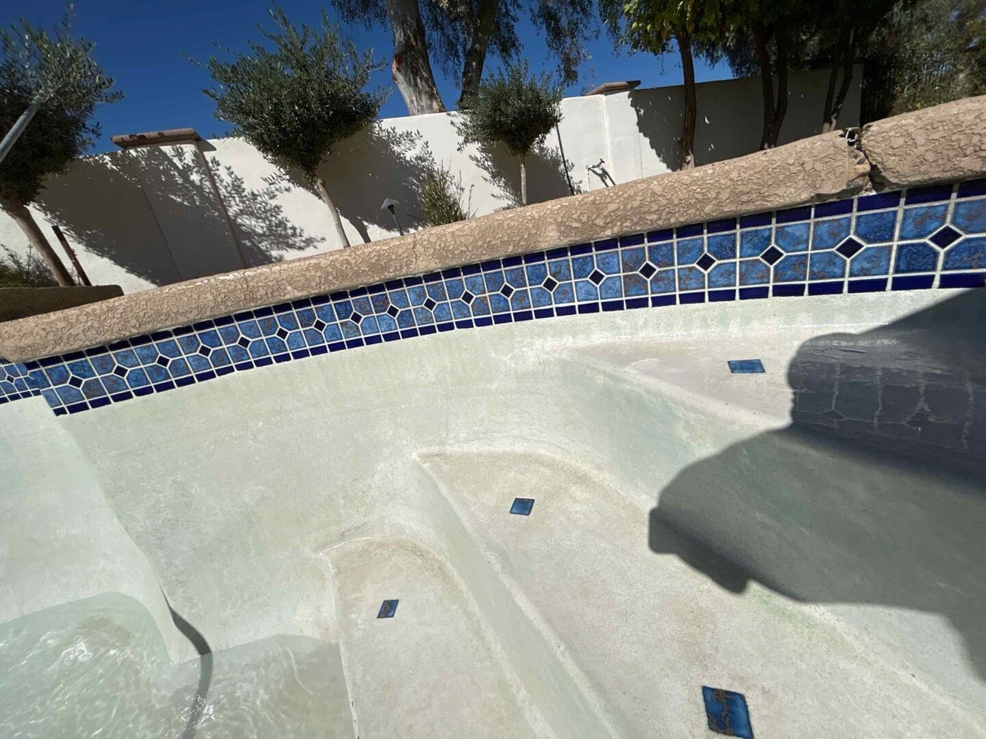 Empty swimming pool with blue tile border.